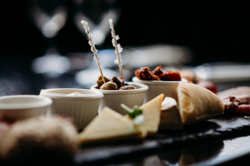 olives on a platter with sundried tomatoes and cheese and breads