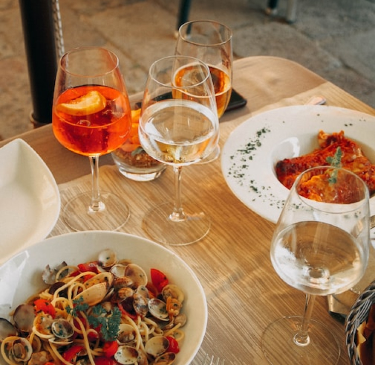 glasses of wine, aperol spritz and a seafood pasta and lasagna