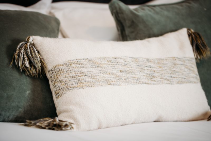 two square green cushions with a rectangle cream cushion with tassels