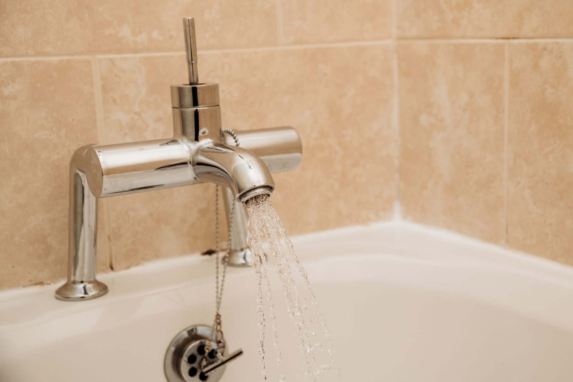 close up of bath tap pouring into bath