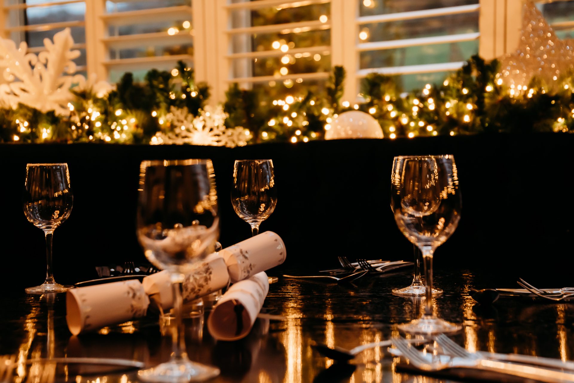 christmas decorations at the window, and a table with four wine glasses and christmas crackers