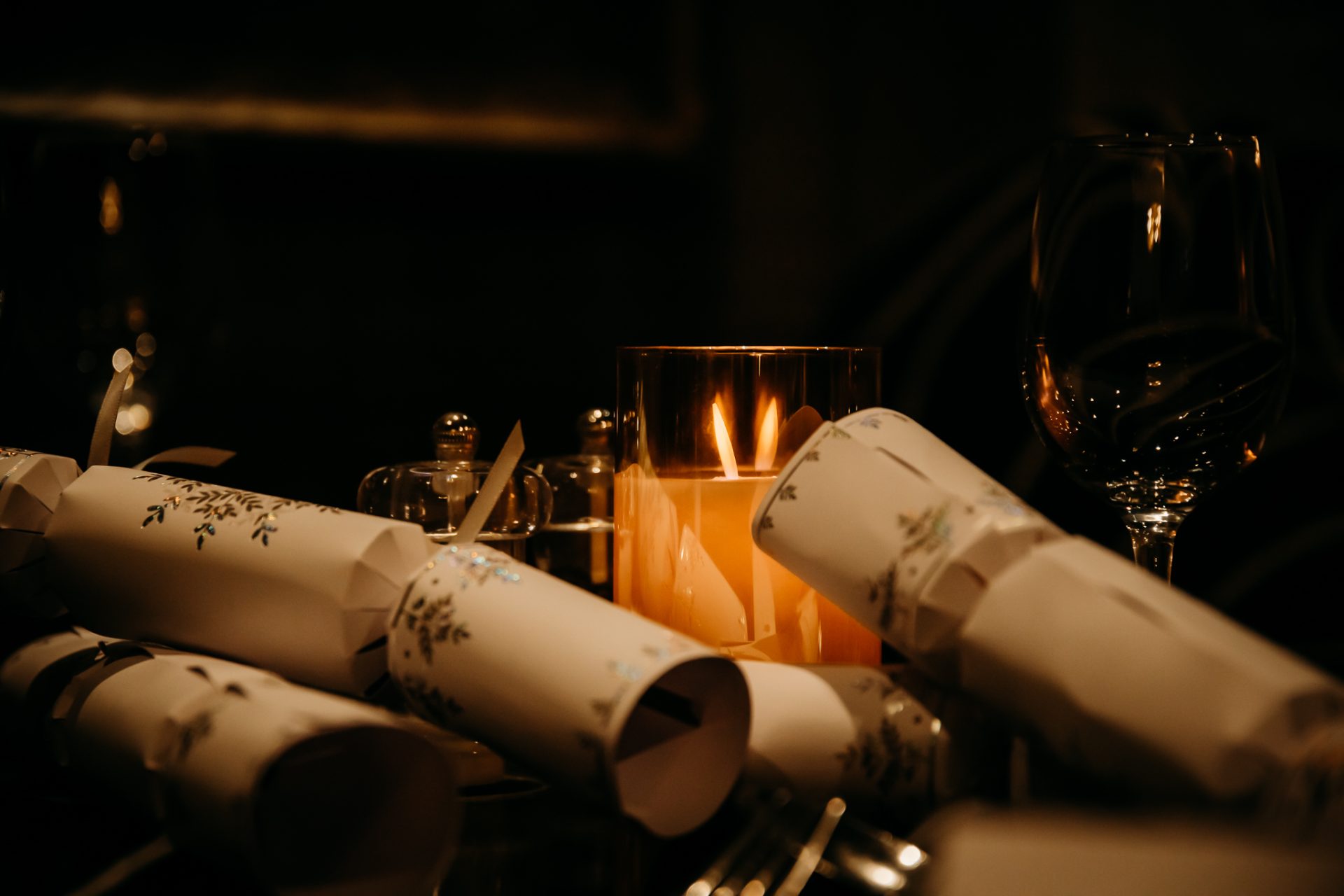 candle lit in the dark with wine glasses and christmas crackers