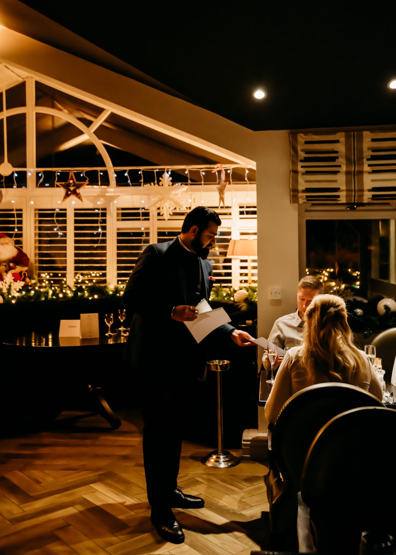 Red Hall Hotel waiter providing menus to a couple having drinks