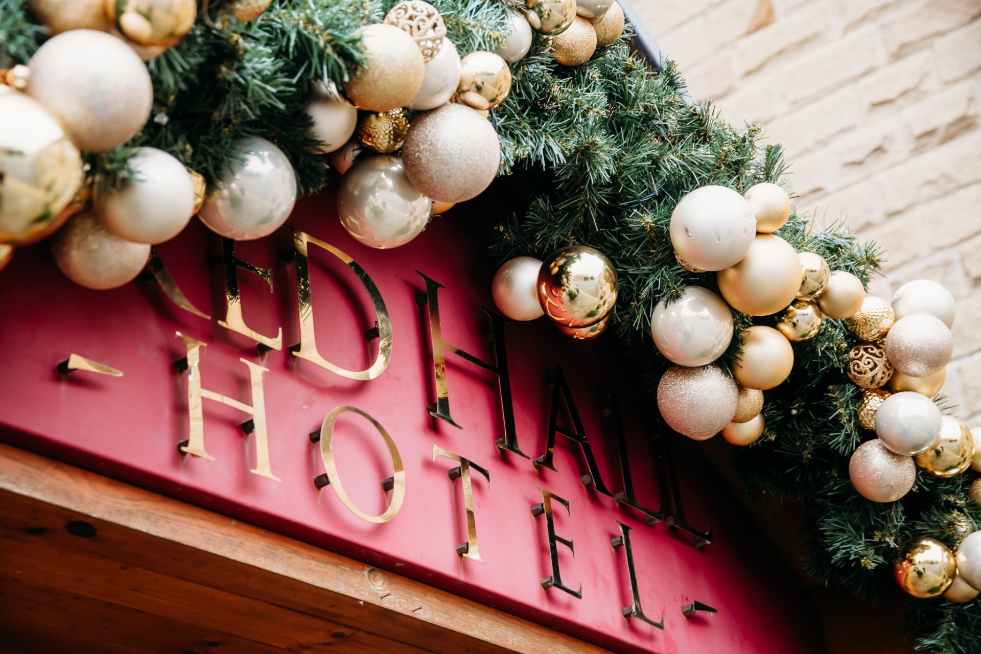 red hall hotel sign with chrismas wreath wrapped at the top and gold and cream baubles attached