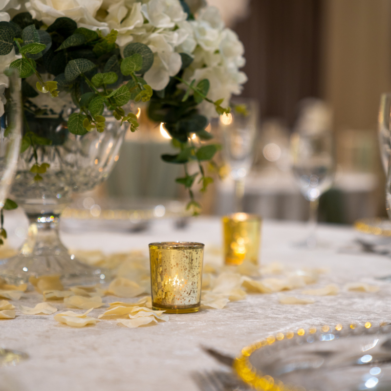 wedding table with vases as centre pieces with white flowers and gold tea light candle holders