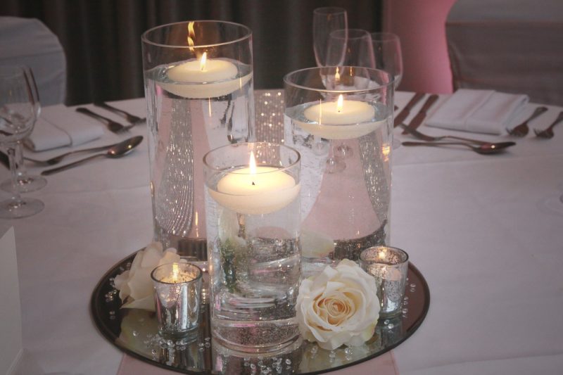 floating candles on a glass table with white roses