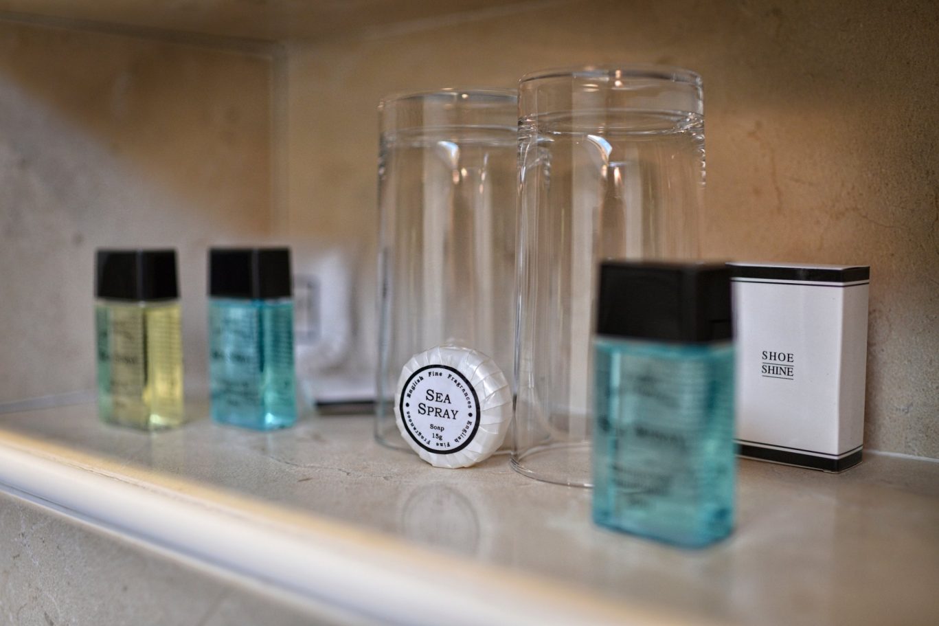 Two drinking glasses, with bathroom items, shoe shine, soap and shampoo