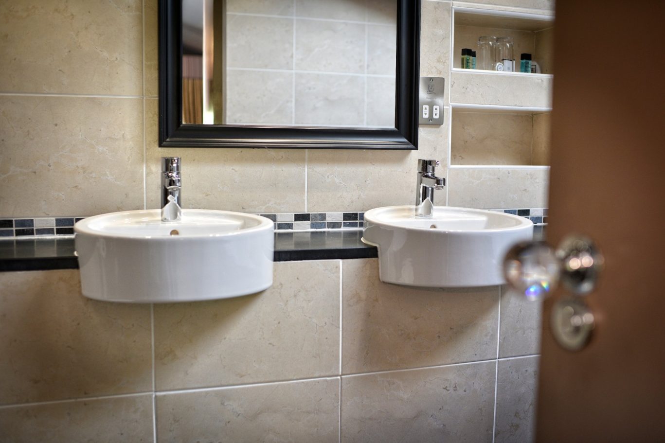 hotel bathroom with two sinks and grey and cream tiles