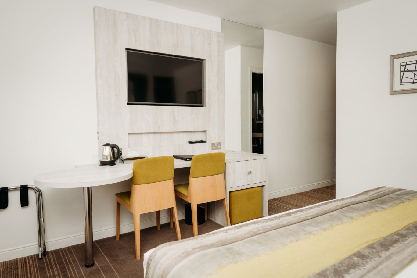 Red Hall Hotel bedroom with two chairs against wall mounted desk and built in tv