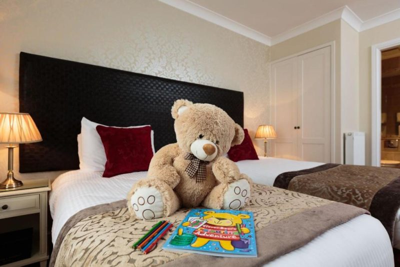 Family room with teddy bear on the end of the bed with a colouring book and pencils
