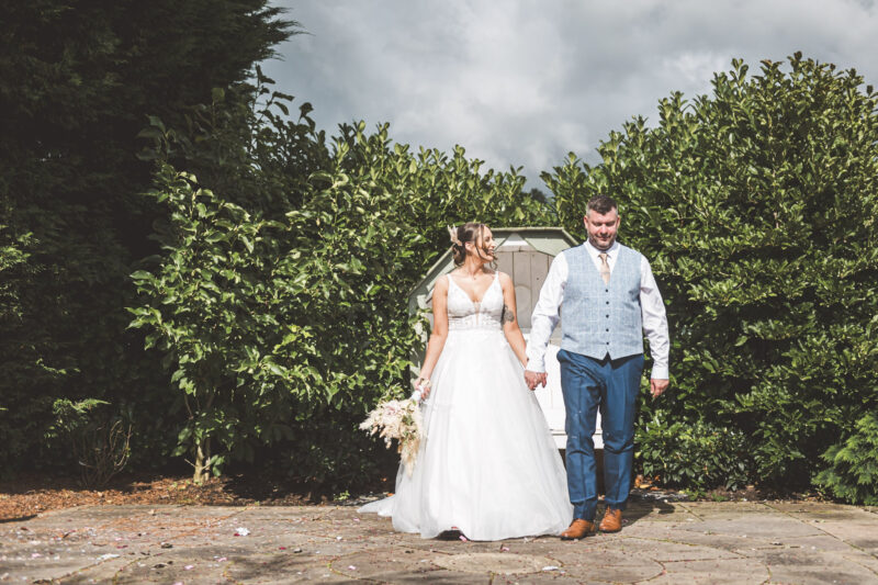 bride looking at groom holding hands walking toward the camera, bride is holding bouquet by her side