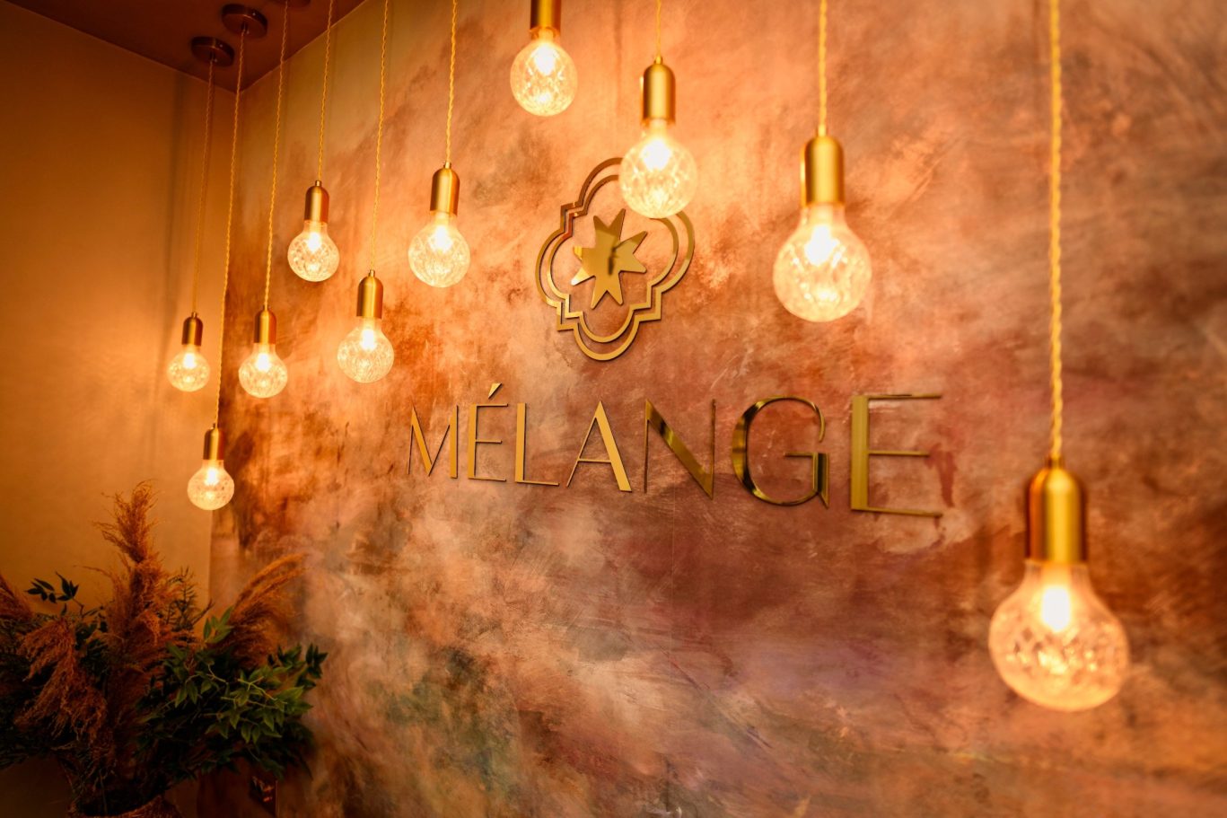 restaurant melange with logo on back wall with mood lightbulbs hanging around the logo
