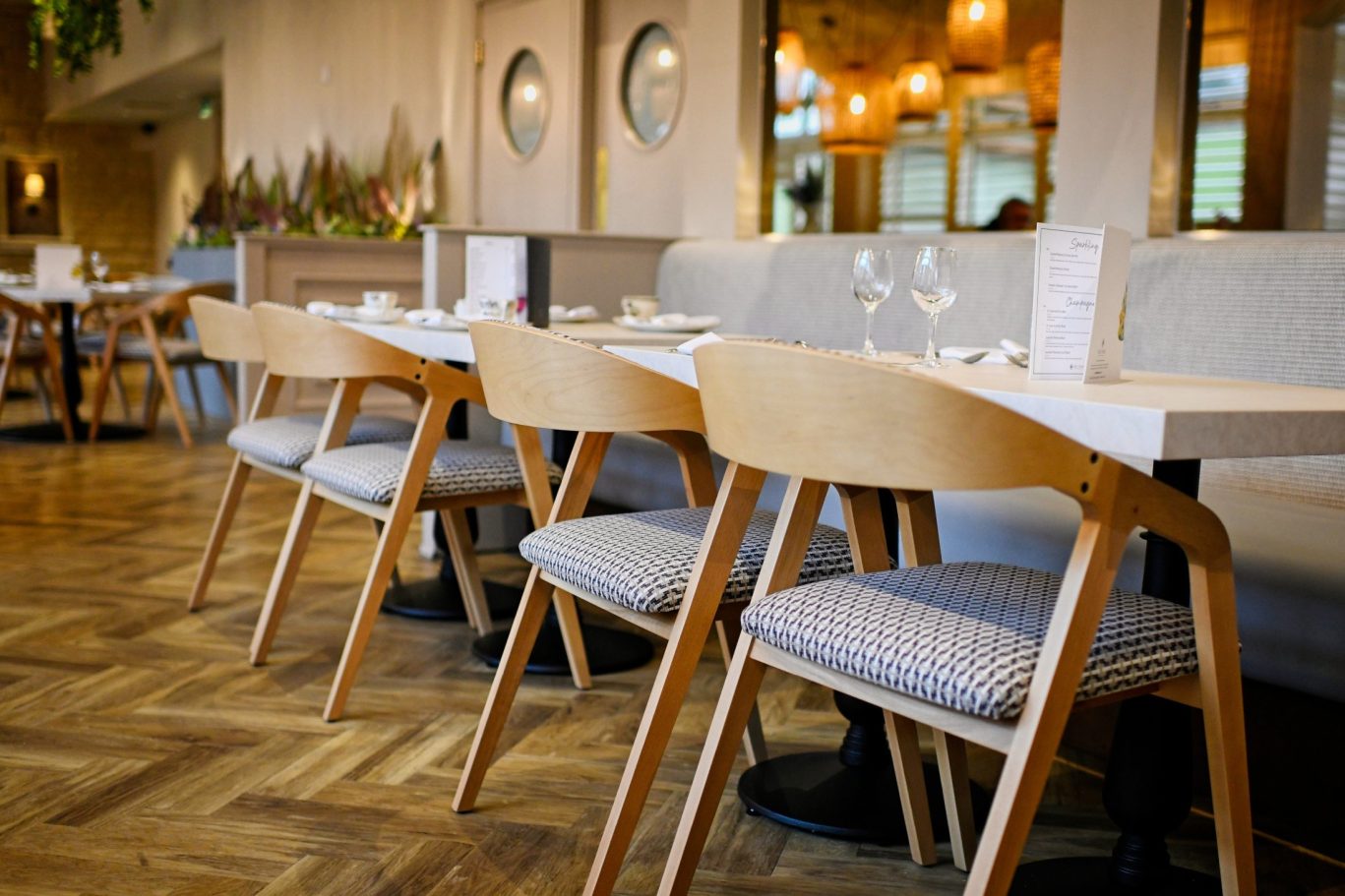 restaurant with chairs in a row, tables set for dinner with wine glasses and menus at melange restaurant