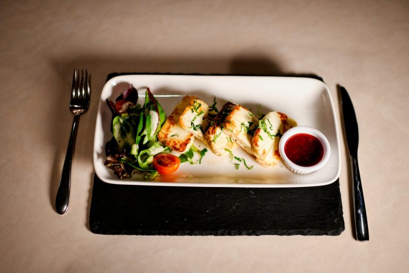 halloumi dish with salad and sauce on a rectangle plate