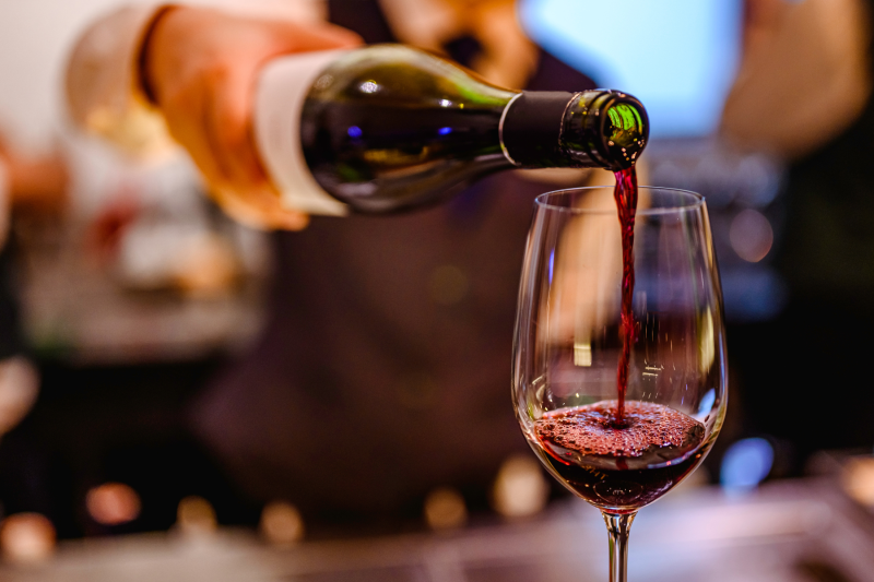 waiter pouring a glass of red wine with blurred background