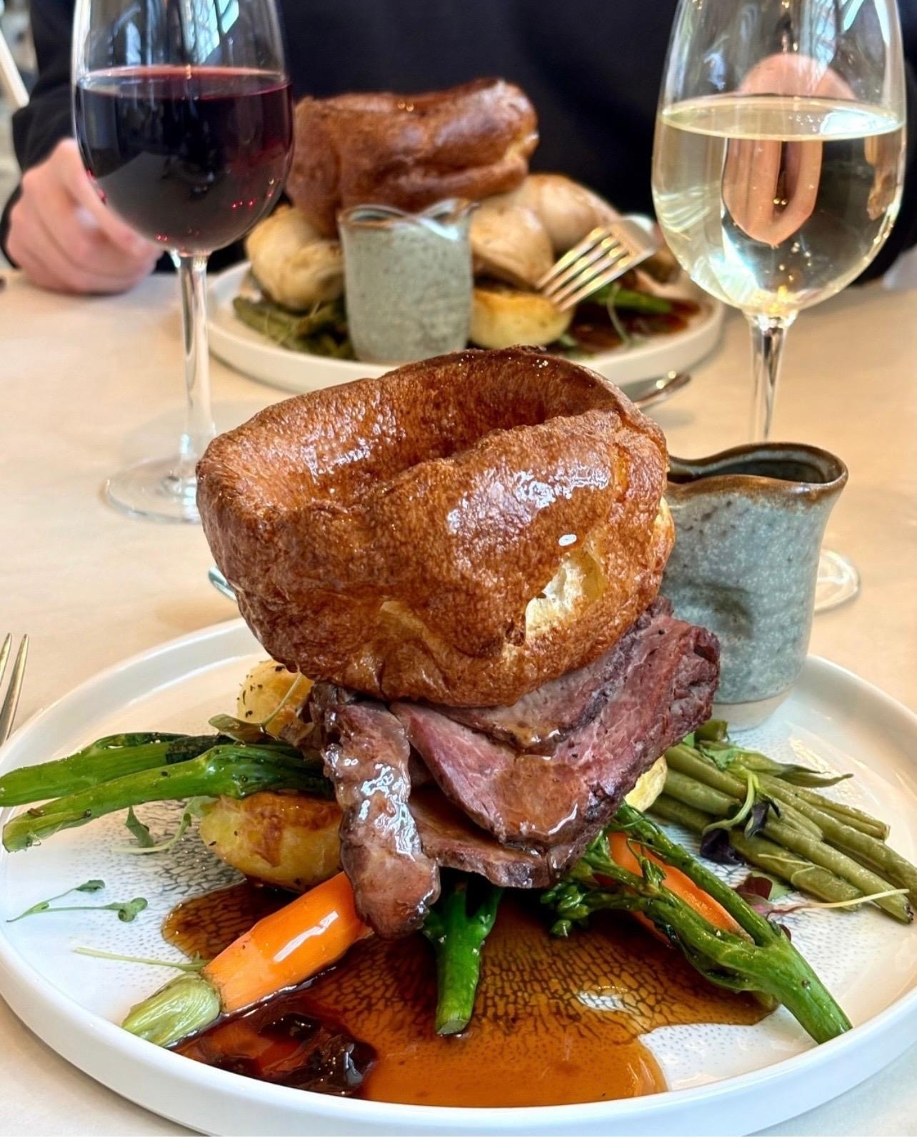 sunday lunch, beef roast dinner with large yorkshire pudding and glass of wine
