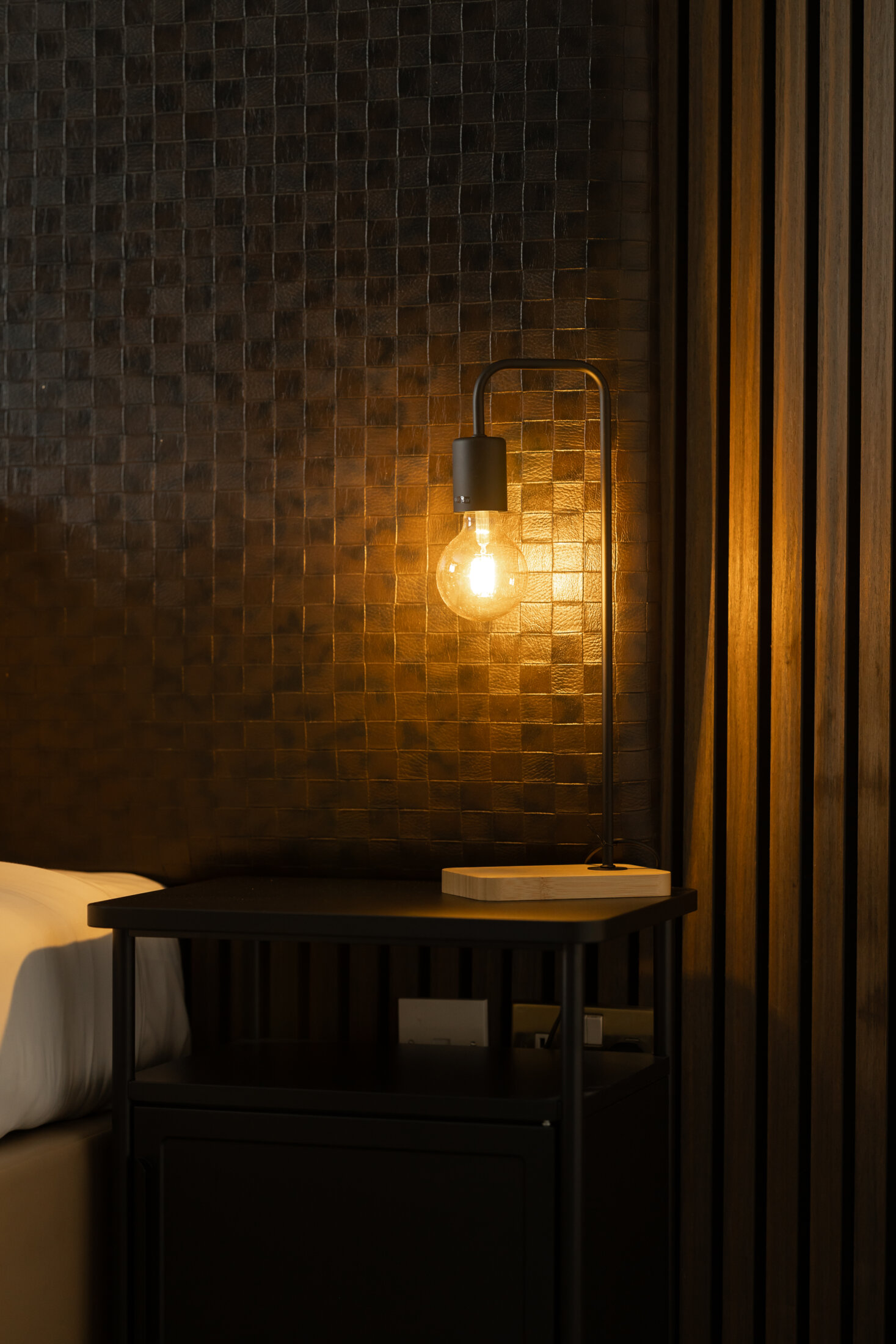 Warm, cosy industrial lighting against a tiled and slatted wall at Red Hall Hotel, Bury