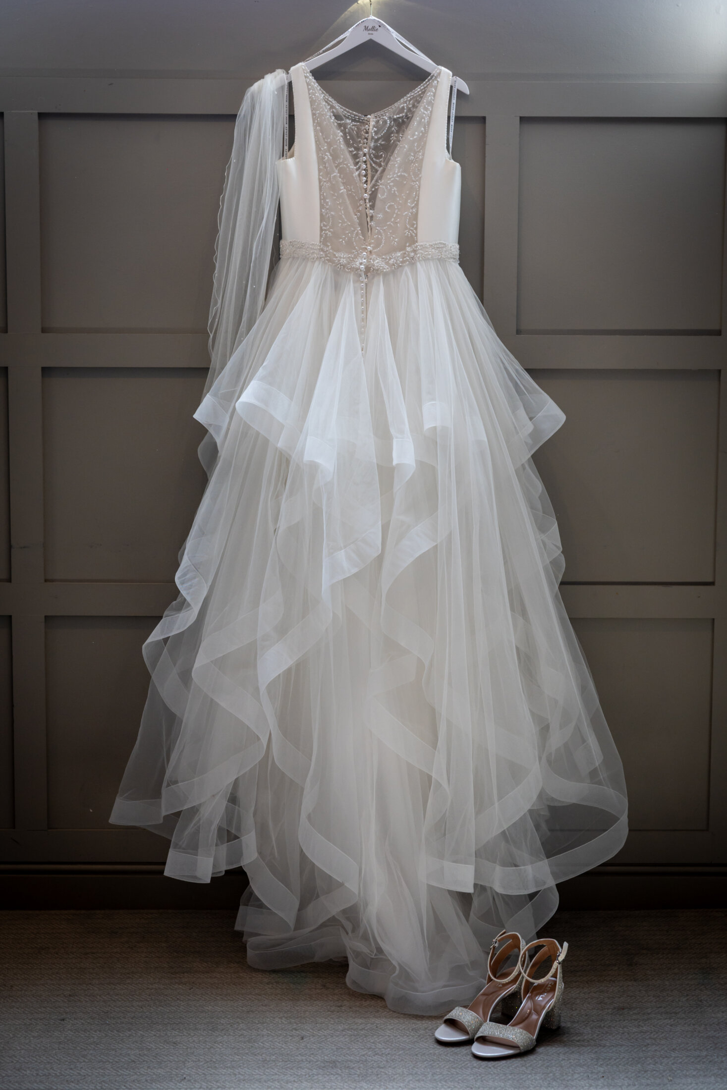 Beautiful white wedding dress and matching bridal shoes hanging up in a suite at Red Hall Hotel, Bury.